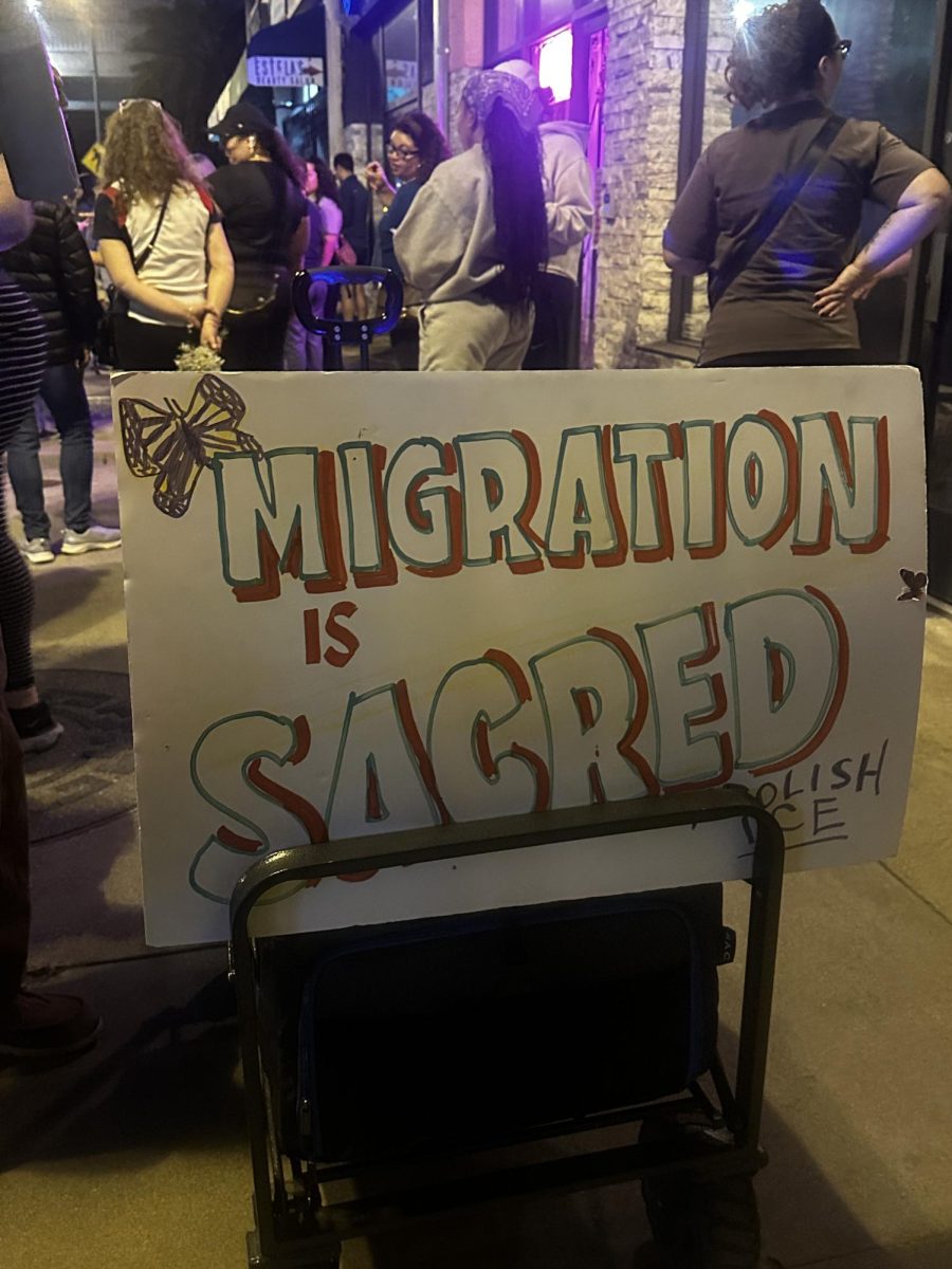 A sign that reads "Migration is Sacred: Abolish ICE", behind a baby stroller during the East Los Angeles Peace Walk.